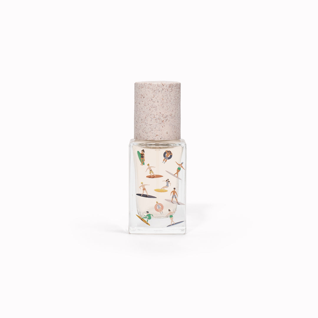 Bain de Midi 15ml bottle, illustrated with pastel surfers. Maison Matine's 'Bain de Midi' is a scent inspired by lightness, simplicity, summer and the joy of being alive, all housed in an illustrative glass bottle. The name means 'midday bath,' an unexpected time for joy and relaxation. The smell of holidays in the sun.