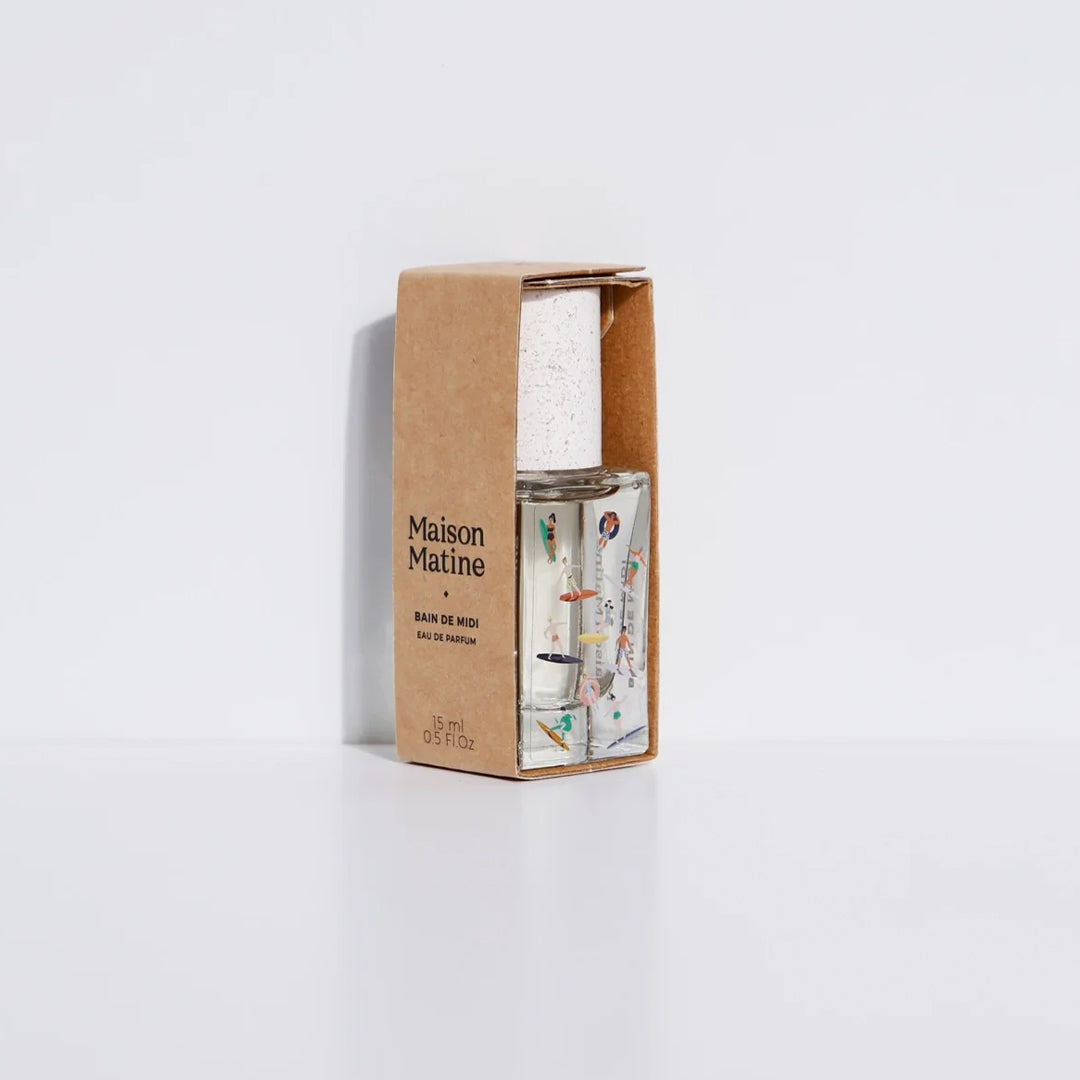 Bain de Midi 15ml bottle, illustrated with pastel surfers, in cardboard sleeve. Maison Matine's 'Bain de Midi' is a scent inspired by lightness, simplicity, summer and the joy of being alive, all housed in an illustrative glass bottle. The name means 'midday bath,' an unexpected time for joy and relaxation. The smell of holidays in the sun.