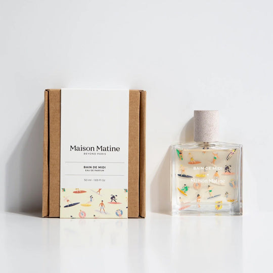 Bain de Midi 50ml bottle, illustrated with pastel surfers, with box. Maison Matine's 'Bain de Midi' is a scent inspired by lightness, simplicity, summer and the joy of being alive, all housed in an illustrative glass bottle. The name means 'midday bath,' an unexpected time for joy and relaxation. The smell of holidays in the sun.