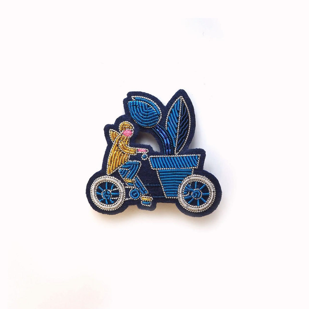 Cargo Bike is a hand embroidered decorative brooch from Macon et Lesquoy in collaboration with Waldorf Astoria Amsterdam. A beautiful Amsterdam inspired lapel pin, featuring a cyclist transporting an oversized plant - a familiar sight on the streets of Amsterdam!