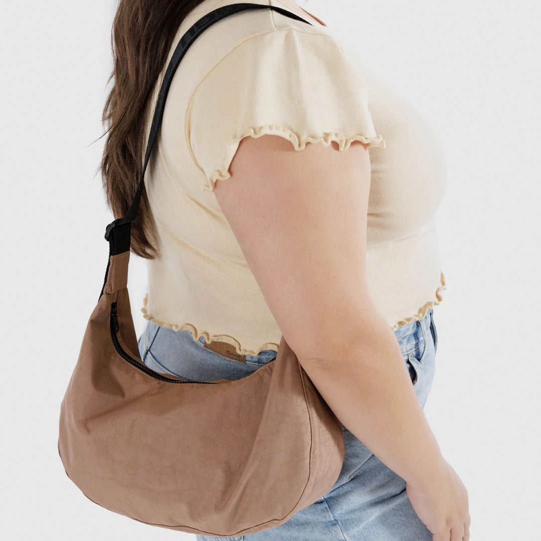 The Medium Crescent Bag in Cocoa from Baggu is a stylish and versatile accessory that can complement any outfit. It is made of durable nylon and features a zippered main compartment - as worn detail