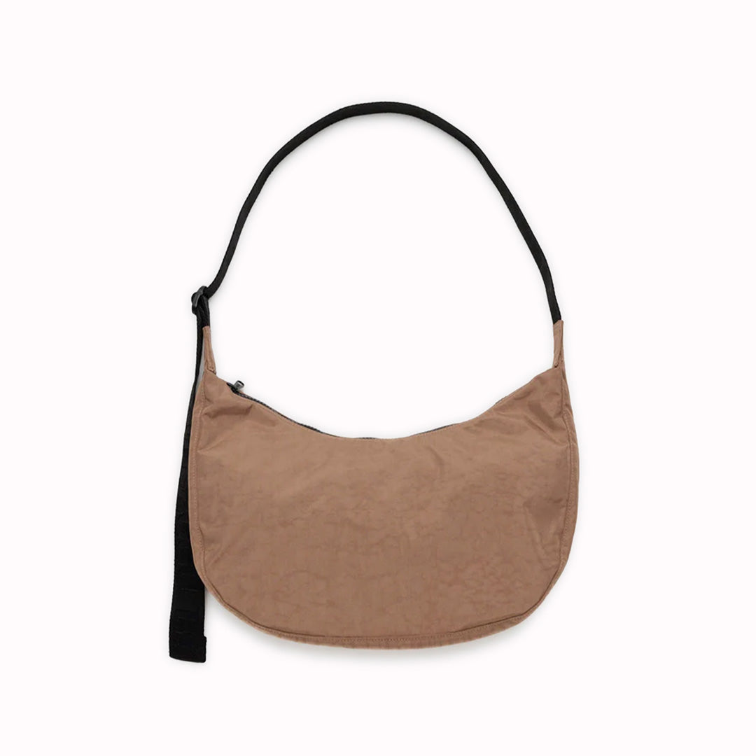 The Medium Crescent Bag in Cocoa from Baggu is a stylish and versatile accessory that can complement any outfit. It is made of durable nylon and features a zippered main compartment