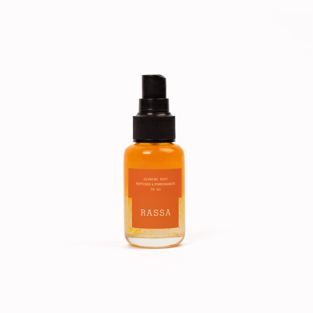 Orange bottle with black cap labeled 'Rassa' Glowing Mist on a white background