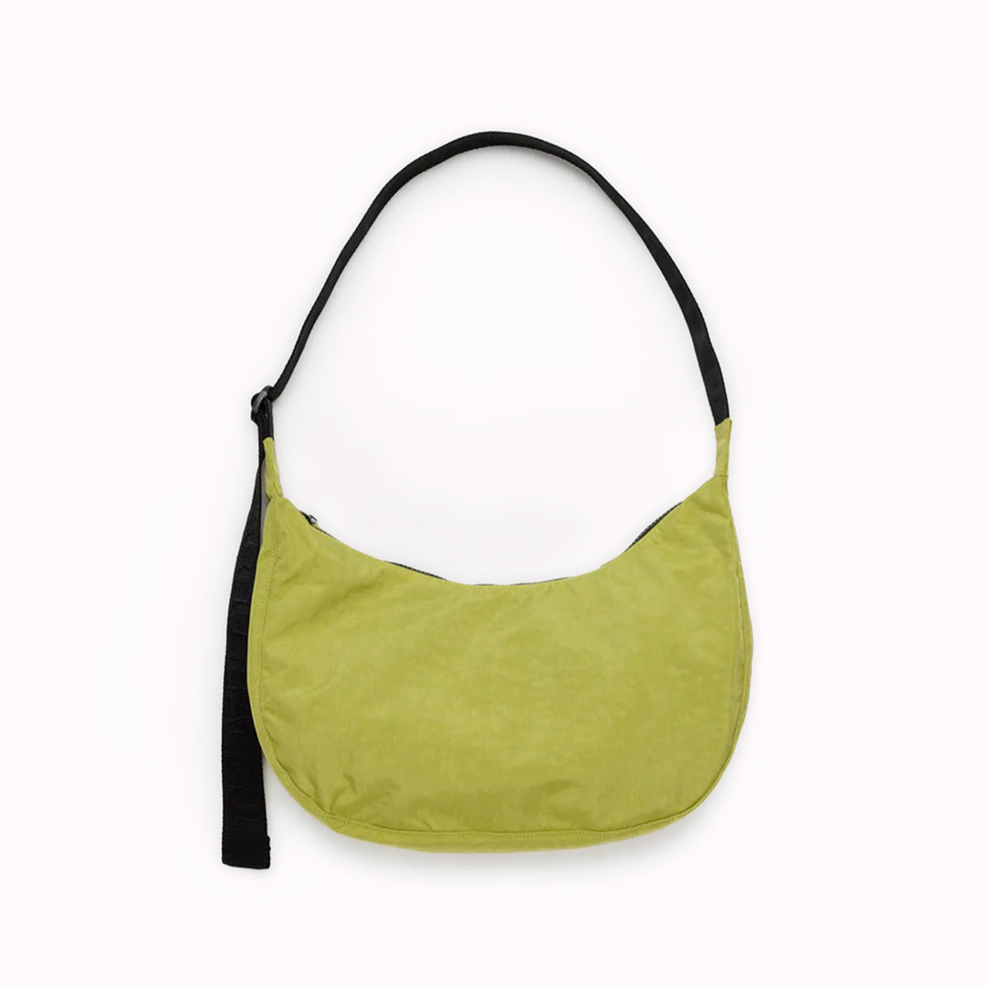 The Medium Crescent Bag in Lemongrass from Baggu is a stylish and versatile accessory that can complement any outfit. It is made of durable nylon and features a zippered main compartment, an interior slip pocket