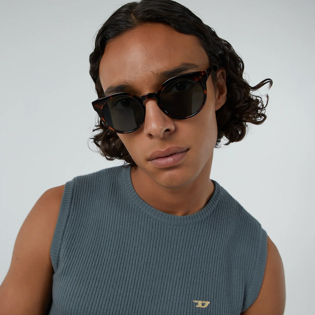 The Lulu as worn by model featuring a unique combination of round lenses set in a cat-eye frame. The Lulu Crystal Giraffe offers unparalleled style and protection with a 133mm x 49.4mm Bio Nylon frame, 100% UV400 lenses, and scratch-resistant PC lens. These gorgeous sunglasses feature a giraffe patterned light and dark brown Bio Nylon frame with solid dark green lenses. Quirky, chic, cool.