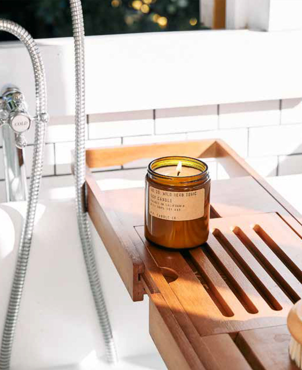 A lifestyle shot of a lit classic line PF Candle scented candle in a bathroom setting