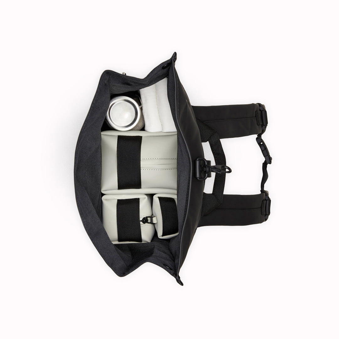Top View of Navy Rolltop Rucksack. Made from Rains’ signature waterproof fabric, this functional backpack has a roll-top closure with an adjustable strap featuring a loop for a bike lock or similar. It has a large main compartment, and an easy-access front pocket and side-access laptop compartment both with a water-repellent zipper closure.