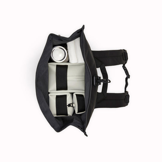 Top View of Navy Rolltop Rucksack. Made from Rains’ signature waterproof fabric, this functional backpack has a roll-top closure with an adjustable strap featuring a loop for a bike lock or similar. It has a large main compartment, and an easy-access front pocket and side-access laptop compartment both with a water-repellent zipper closure.