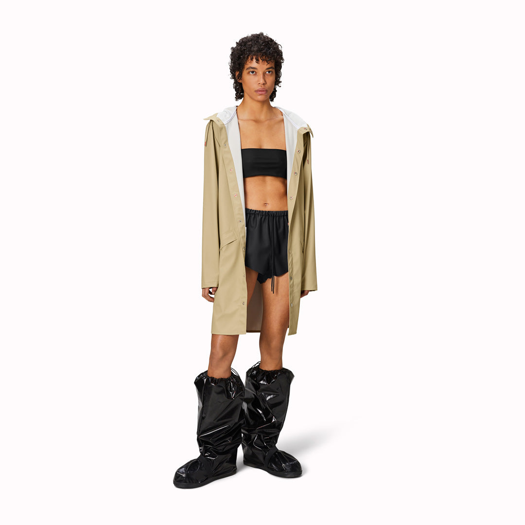 contemporary unisex rain jacket from Danish Outerwear and Lifestyle company Rains. This long Sand coloured rain jacket is characterized by a minimal silhouette in a long design.