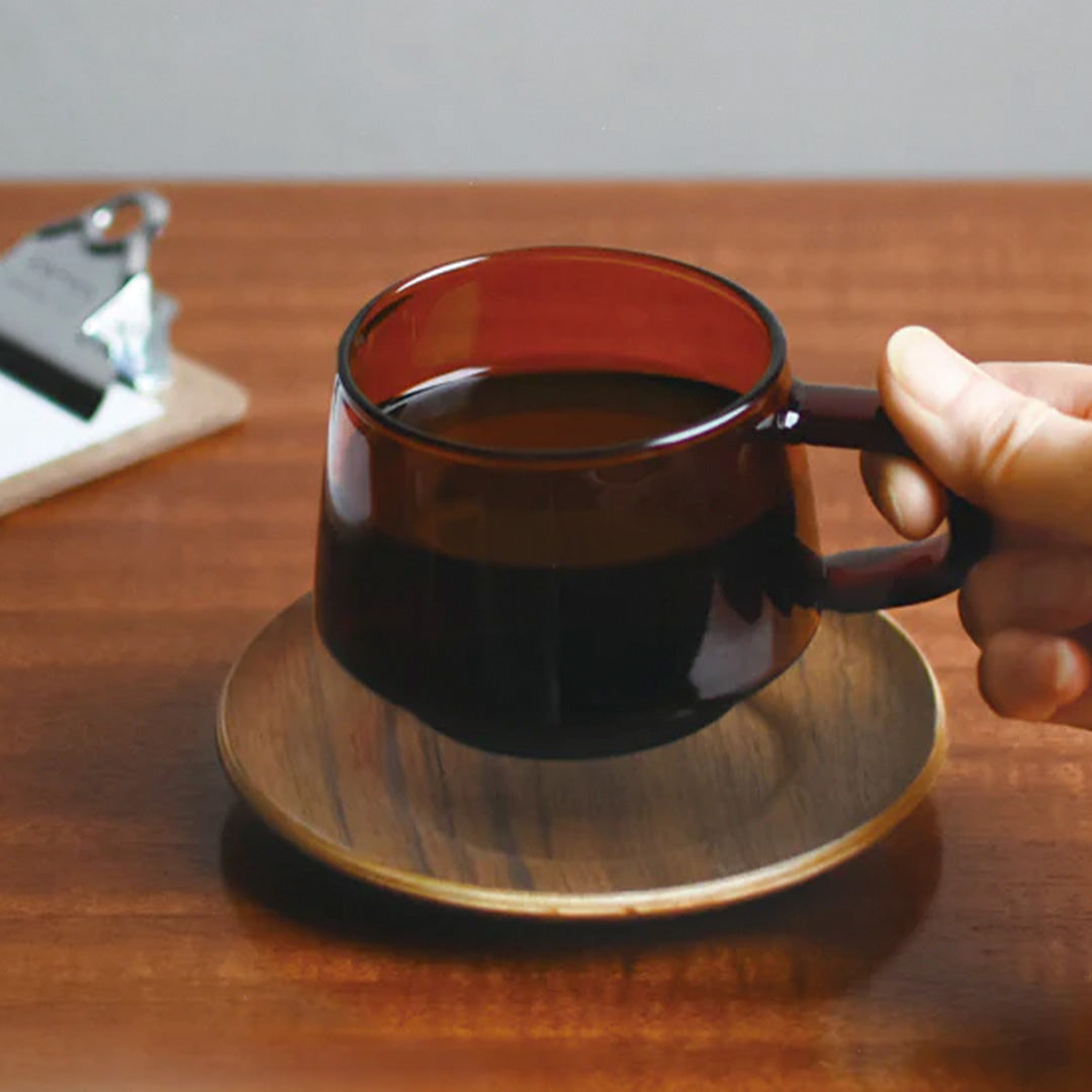 The Sepia teak saucer by Kinto Japan is a stylish and functional accessory for your coffee or tea time. The saucer is made of natural teak wood, which has a warm and rich color and a smooth texture. Teak saucer with sepia toned glass cup.