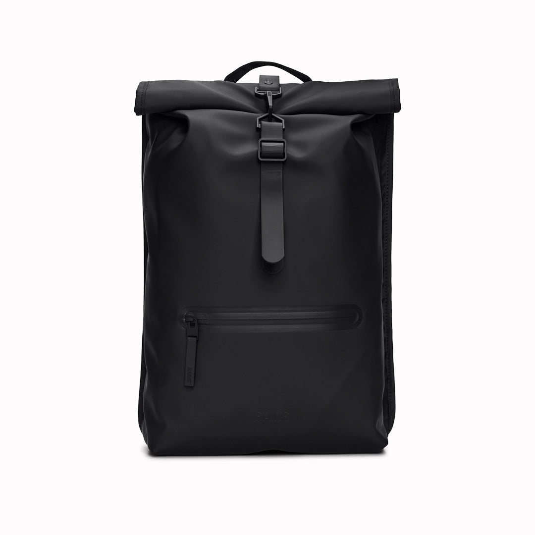 Front View of Black Rolltop Rucksack. Made from Rains’ signature waterproof fabric, this functional backpack has a roll-top closure with an adjustable strap featuring a loop for a bike lock or similar. It has a large main compartment, and an easy-access front pocket and side-access laptop compartment both with a water-repellent zipper closure.