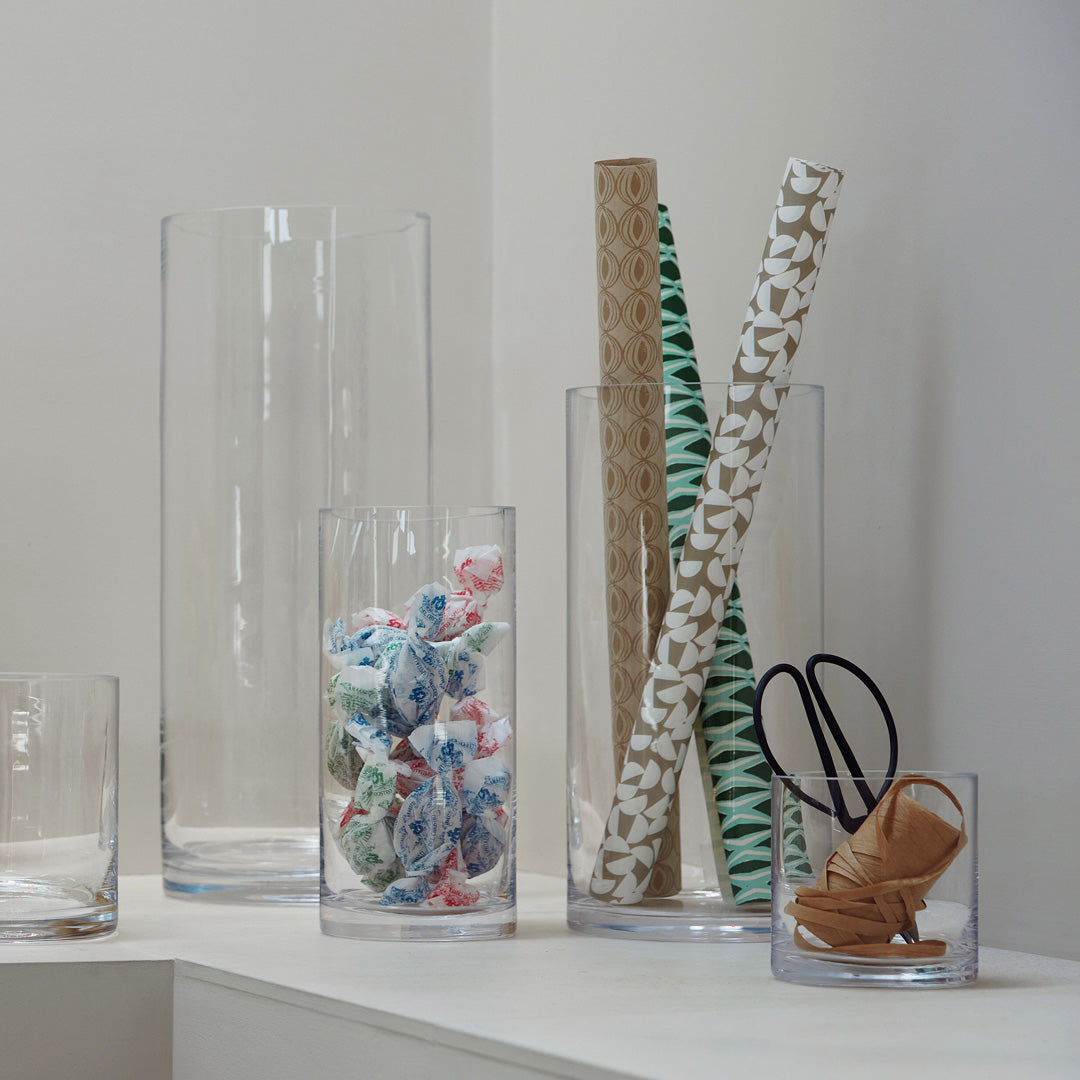 Collection on shelf, The Column Vase from LSA is a contemporary, straight sided cylindrical vase made from clear mouth blown glass. The Column Vase features a heavy base, thick walls and cut and polished rims with all finishing done by hand.