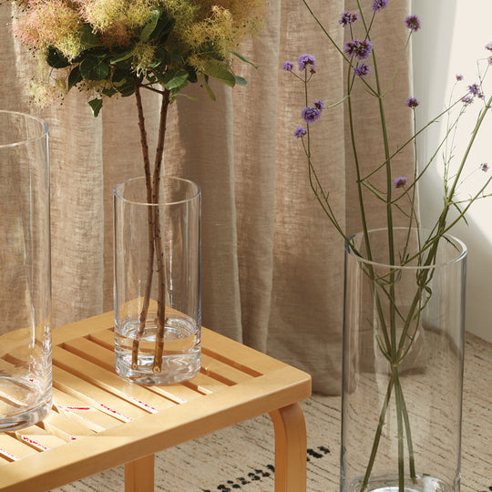 Collection on table, The Column Vase from LSA is a contemporary, straight sided cylindrical vase made from clear mouth blown glass. The Column Vase features a heavy base, thick walls and cut and polished rims with all finishing done by hand.