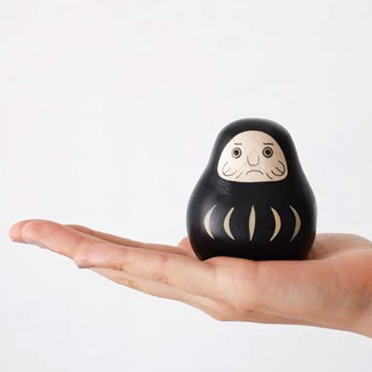 Daruma Doll Engimon handmade wooden figurine by T-Lab Japan, in hand.
