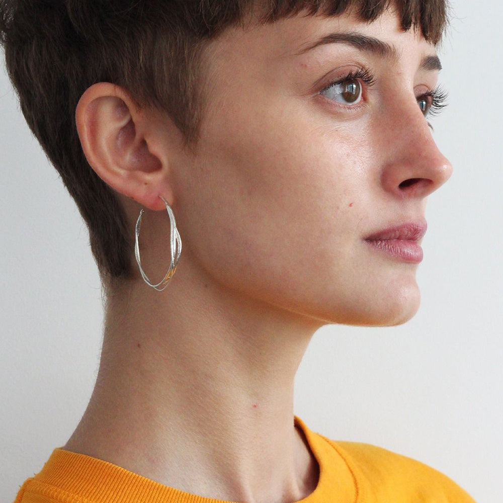 A single vine has curled and twisted around itself to create a pair of elegant, contemporary hoop earrings. Perfect for mixing and matching with other Alex Monroe earrings.