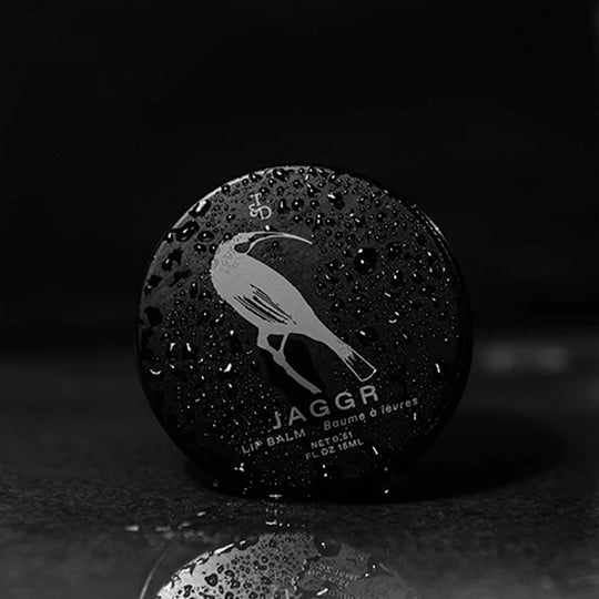 Jaggr, Triumph and Disaster's natural SPF 15 lip balm is SPF 15 protecting your lips from drying out in the sun but is also hydrating with manuka and kawakawa oils to moisten and protect lips from chapping and drying out. - lifestyle image, lip balm tin with drops of water.