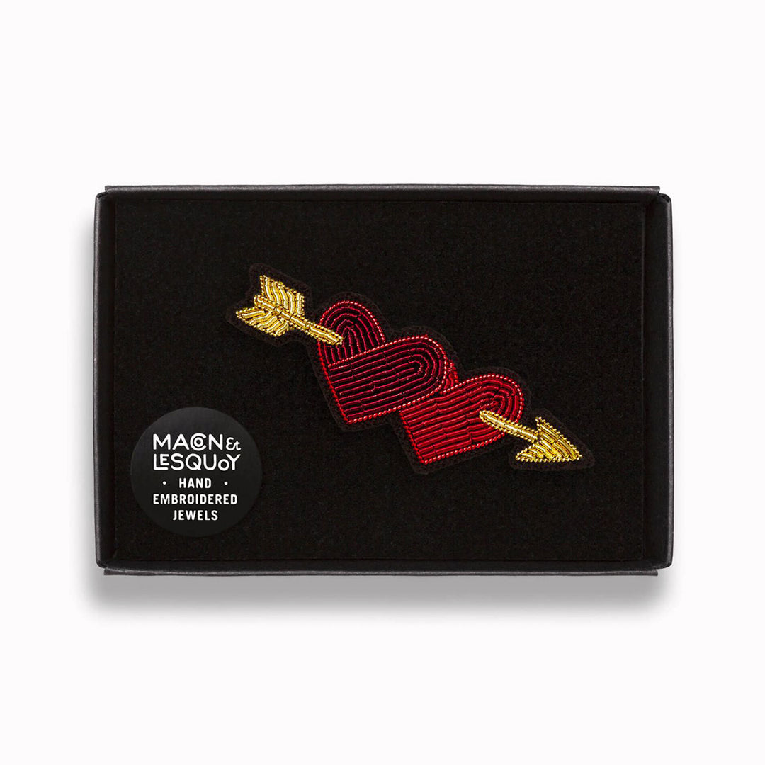 A gorgeous hand-embroidered lapel pin showing two hearts pierced with Cupid's arrow in a presentation box From Macon & Lesquoy, French Hand Embroidered badges and patches using Cannetille thread.