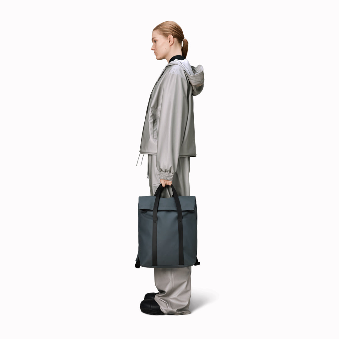 The Rains 2 Way Tote Backpack is characterised by a fold-top opening with the addition signature TPU strap details with top handles.