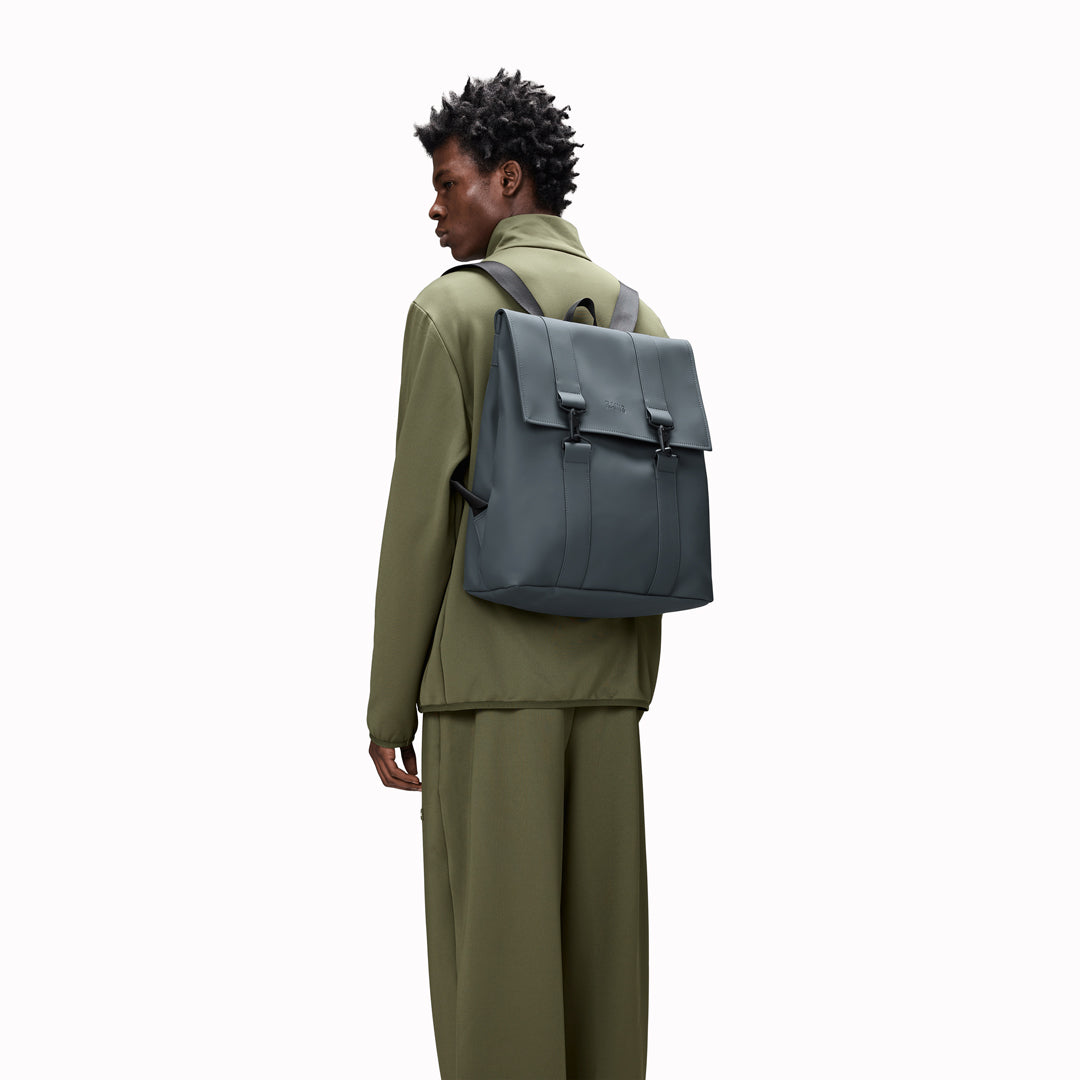 Rains' MSN Bag W3 is their interpretation of the classic school backpack, reimagined for commuters. A minimal silhouette with dual strap and carabiner closure. Made from Rains’ signature waterproof fabric