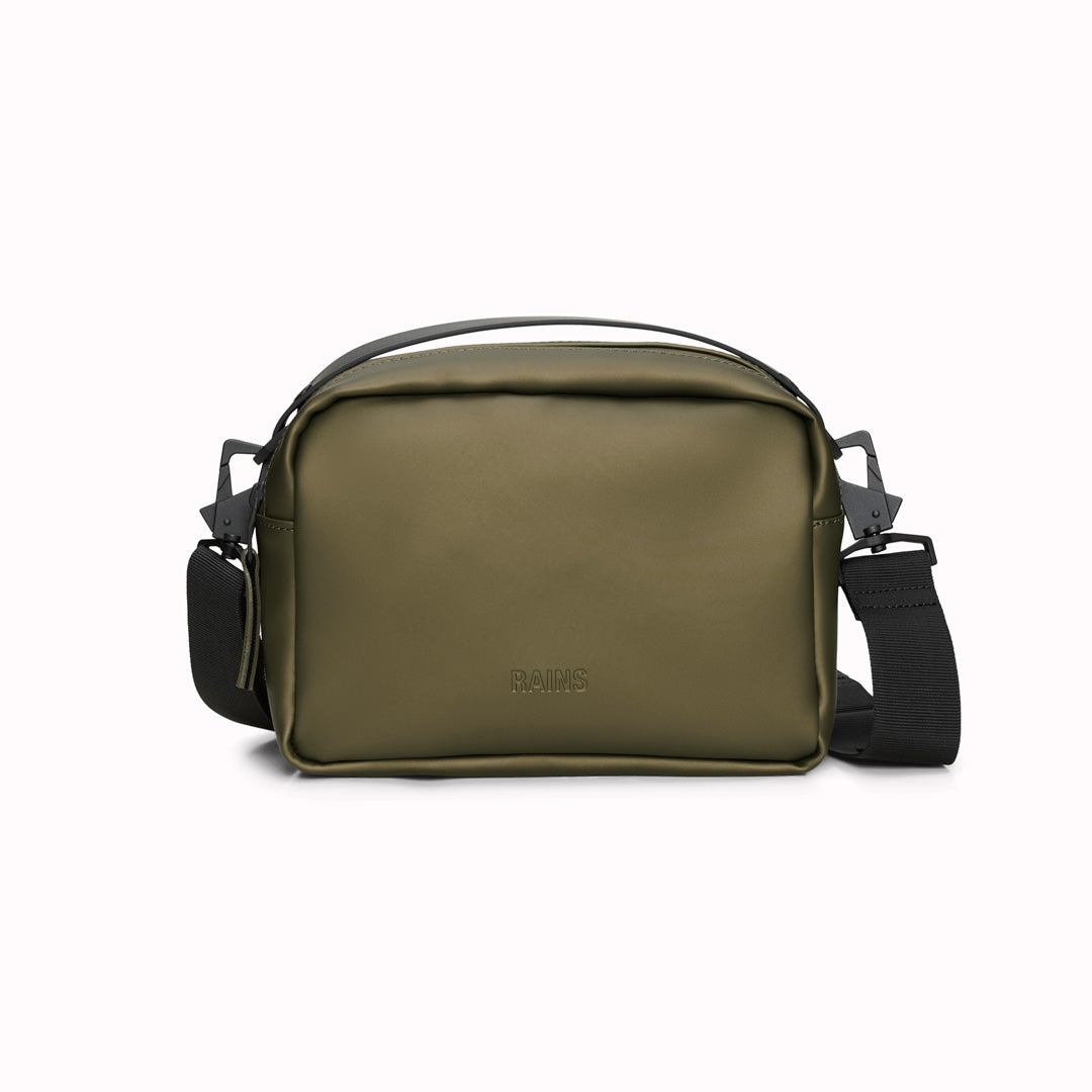 The Rains Box Bag in green is a sleek and minimalist bag crafted from Rains' signature waterproof PU fabric. It features a boxy silhouette with clean lines and a single main compartment secured by a coated zip closure.