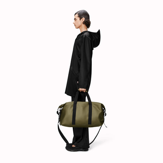 The Hilo Weekend Bag by Rains is a great contemporary gym or overnight bag. It features a single main compartment, carry handles, a detachable shoulder strap, and adjustable lock slider buckles on the sides. This brilliant waterproof duffel bag is cut from Rains’ signature waterproof PU coated fabric and is finished with coated zip and matte hardware.