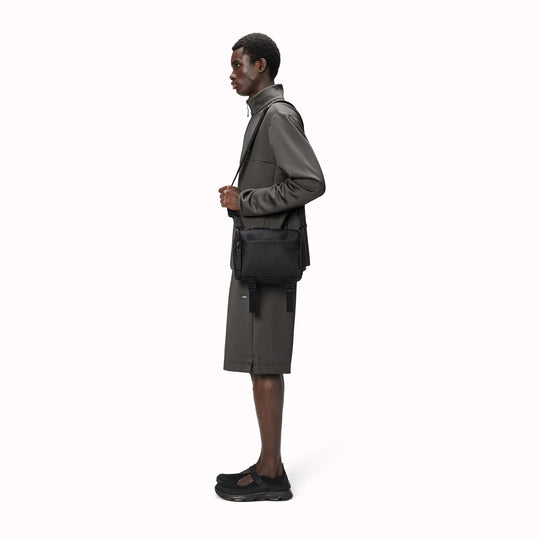 The Rains Texel Crossbody bag in black is a sleek and functional accessory designed for travel and everyday use. Crafted from Rains' signature waterproof matte-shell material, this bag offers durable protection against the elements.