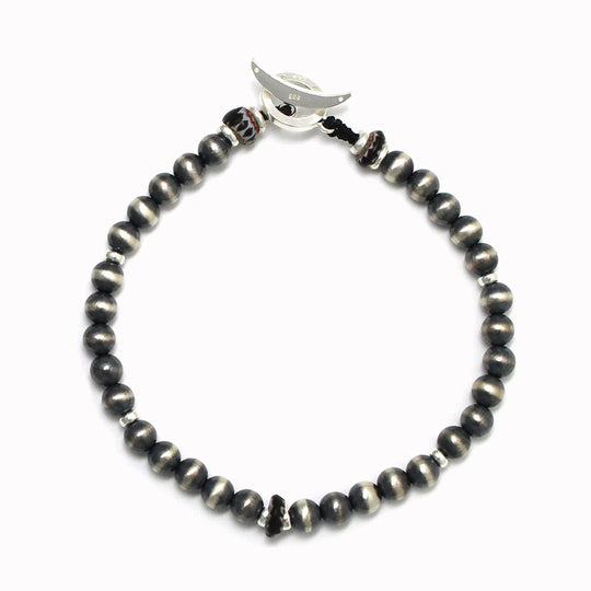 Mikia are a small batch hand made Japanese jewellery brand specialising in mens bracelets and necklaces using the finest natural stone and beads. This wrap bracelet made from 5mm round, silver najavo pearl beads with vintage glass black chevron beads as the highlight colour and a sterling silver clasp.