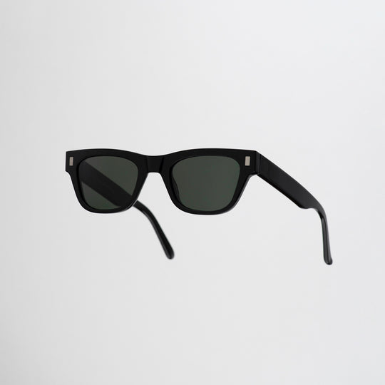 Monokel Aki Sunglasses in Black with a solid green lens sits low on the bridge with a slim, rectangular profile that keeps things sharp