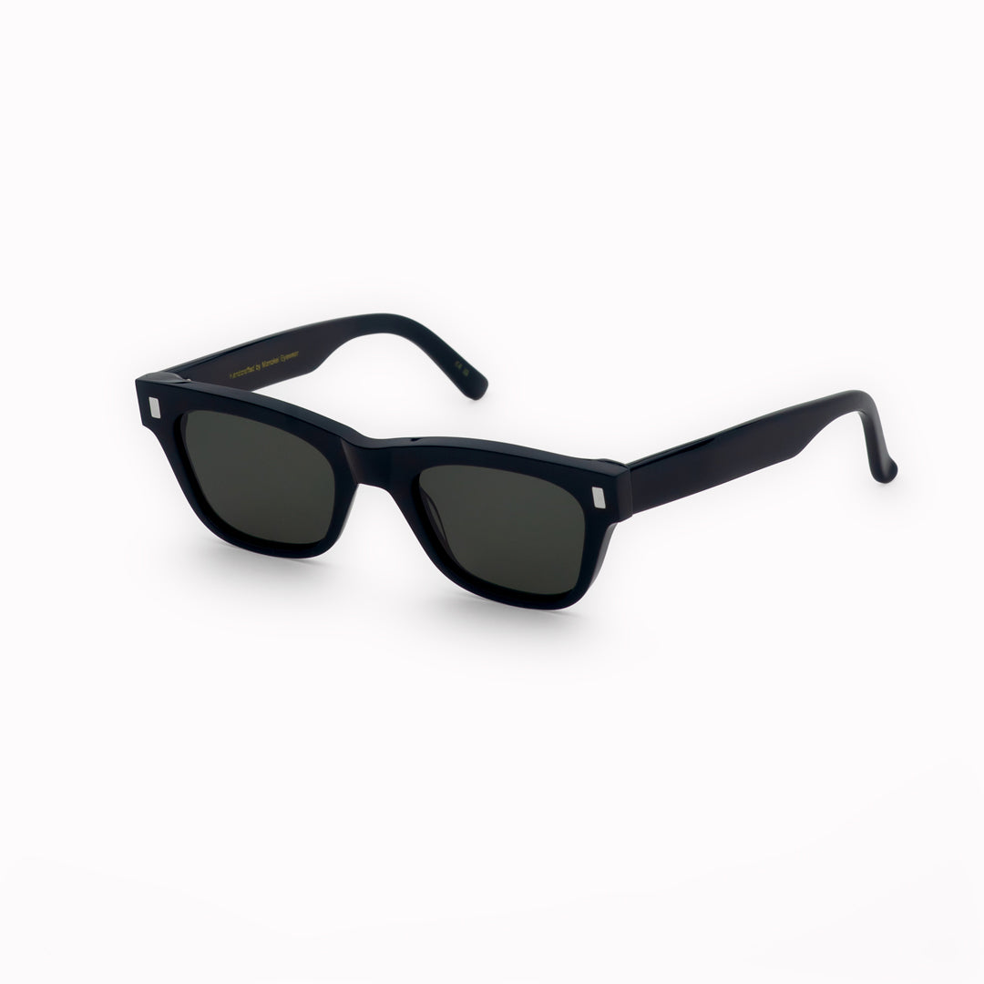 Monokel Aki Sunglasses in Black with a solid green lens sits low on the bridge with a slim, rectangular profile that keeps things sharp