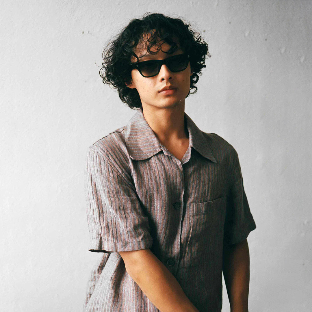 Monokel Aki Sunglasses in Black with a solid green lens sits low on the bridge with a slim, rectangular profile that keeps things sharp