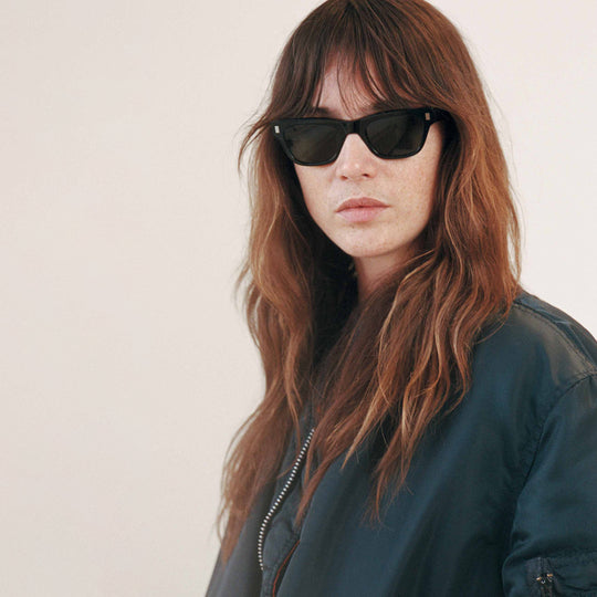 Monokel Aki Sunglasses in Black with a solid green lens sits low on the bridge with a slim, rectangular profile that keeps things sharp