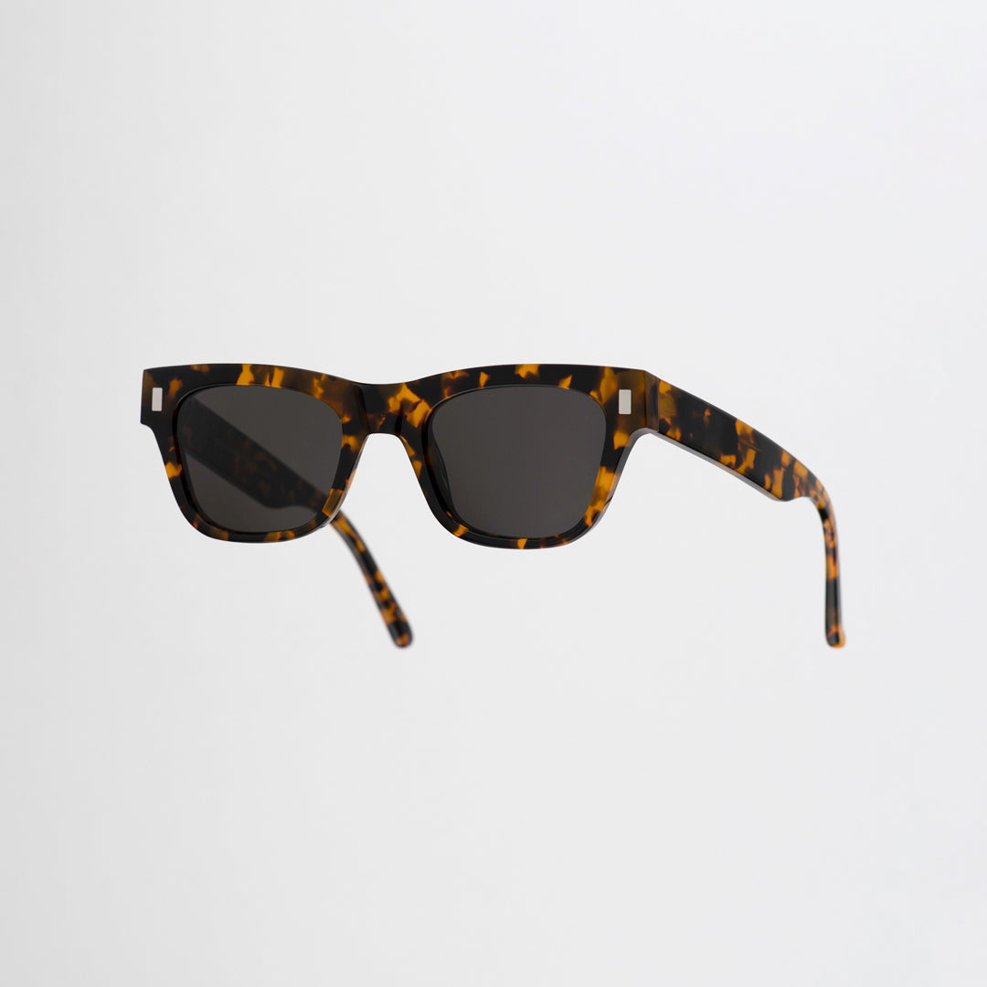 Monokel Aki Sunglasses with a Havana frame with a solid grey lens sits low on the bridge with a slim, rectangular profile that keeps things sharp