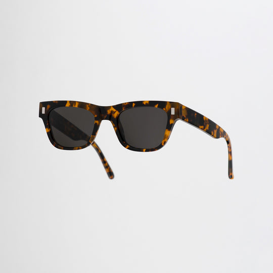 Monokel Aki Sunglasses with a Havana frame with a solid grey lens sits low on the bridge with a slim, rectangular profile that keeps things sharp