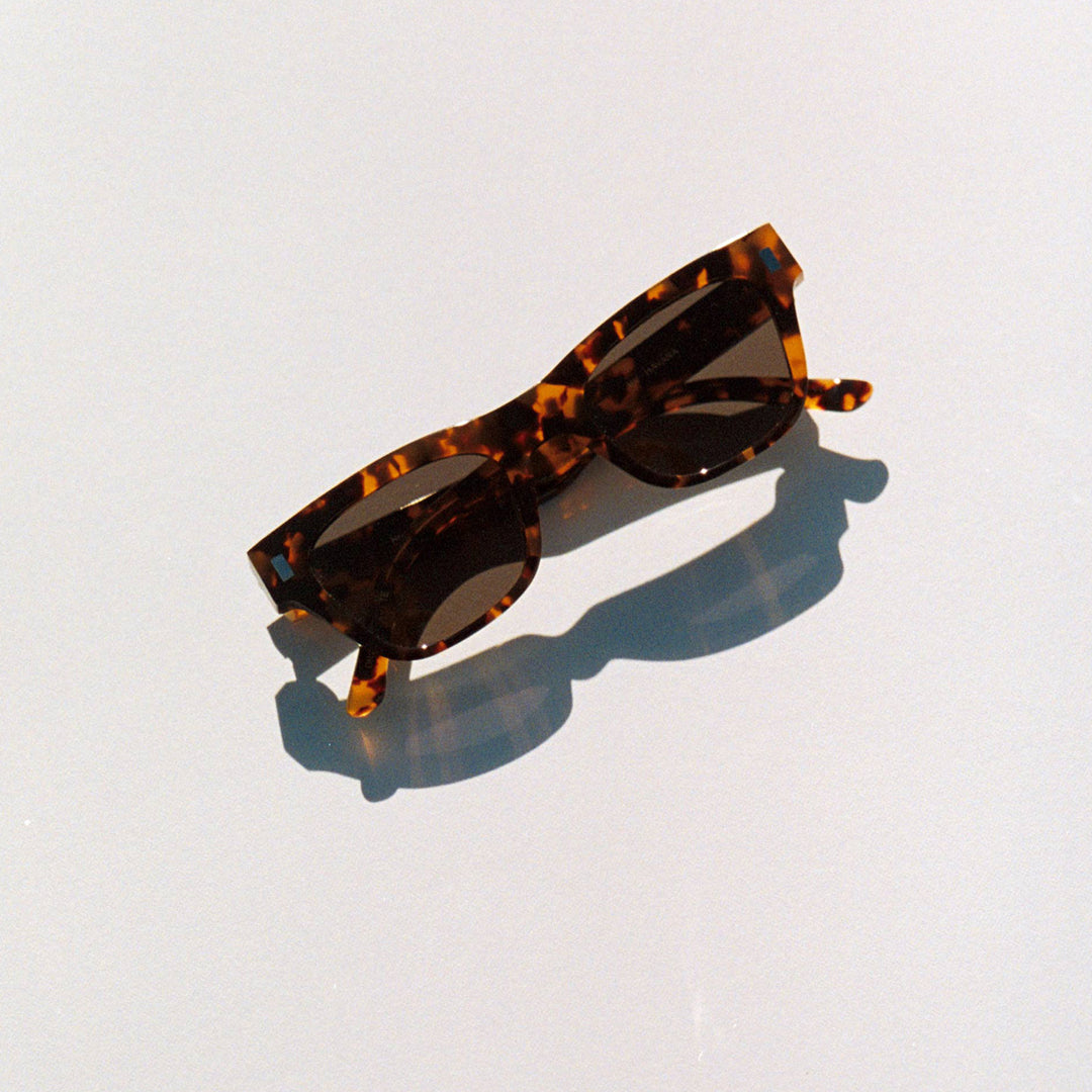 Monokel Aki Sunglasses with a Havana frame with a solid grey lens sits low on the bridge with a slim, rectangular profile that keeps things sharp