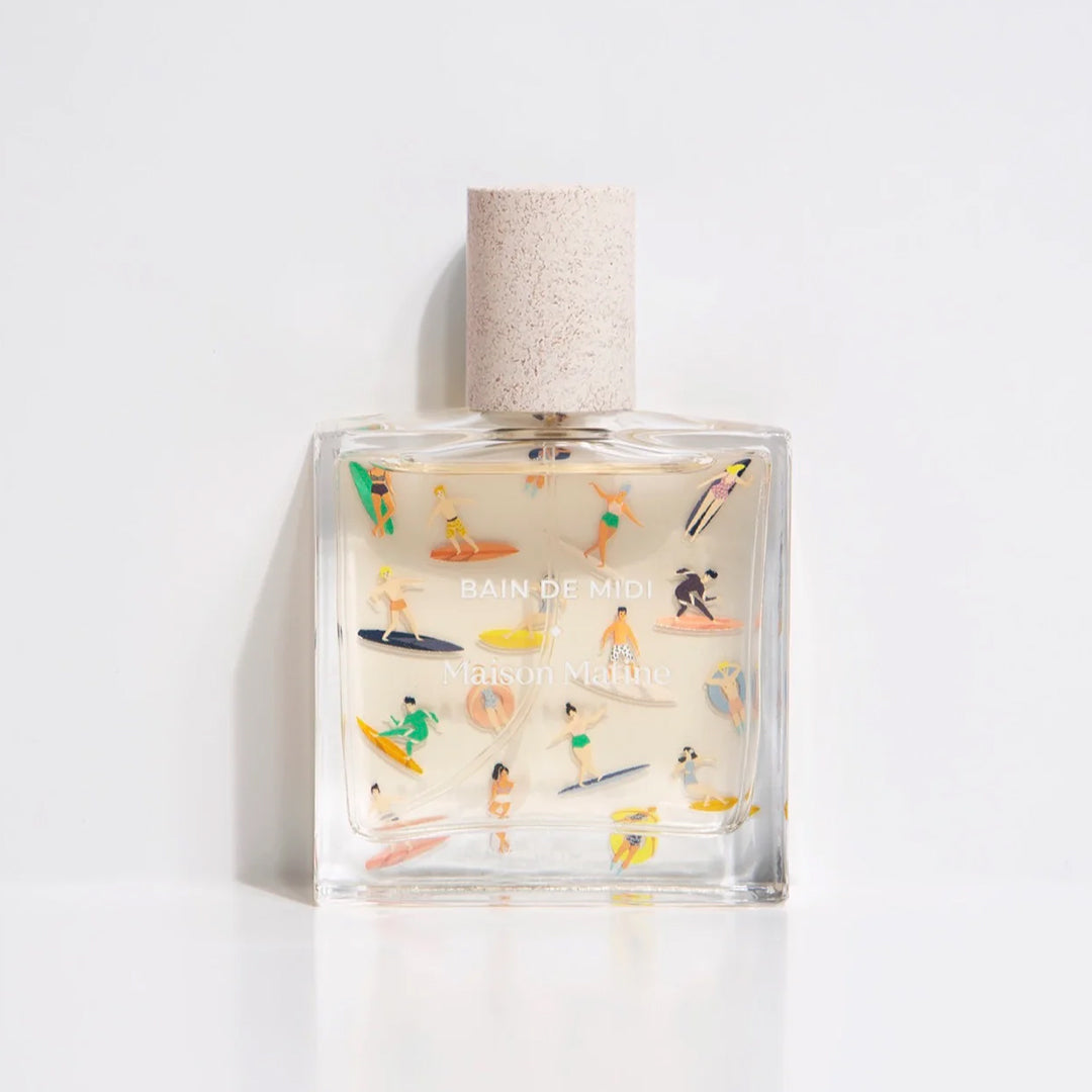 Bain de Midi 50ml bottle, illustrated with pastel surfers. Maison Matine's 'Bain de Midi' is a scent inspired by lightness, simplicity, summer and the joy of being alive, all housed in an illustrative glass bottle. The name means 'midday bath,' an unexpected time for joy and relaxation. The smell of holidays in the sun.