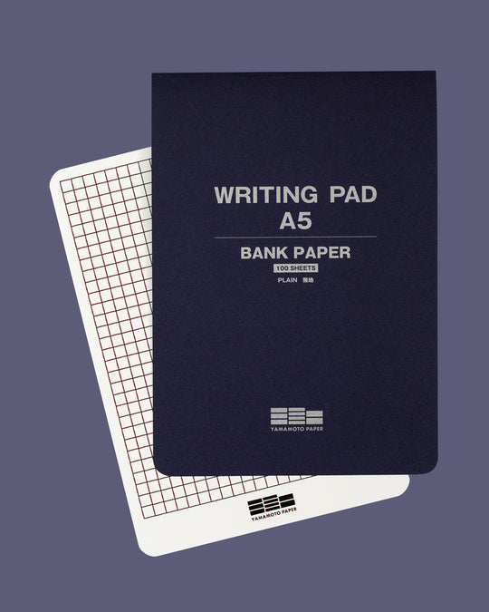 The pad is glue bound along the top edge for easy sheet removal, and the pad includes a removable guide sheet with grid layout on one side and ruled layout on the other.