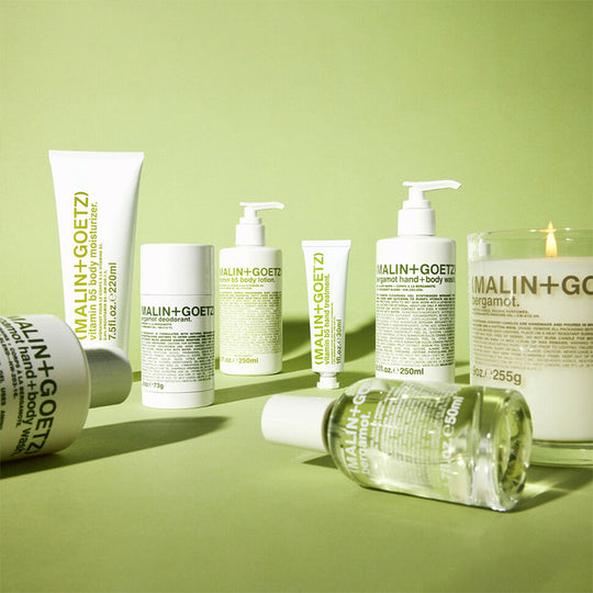 Collection of Malin+Goetz Bergamot skincare products on a green background