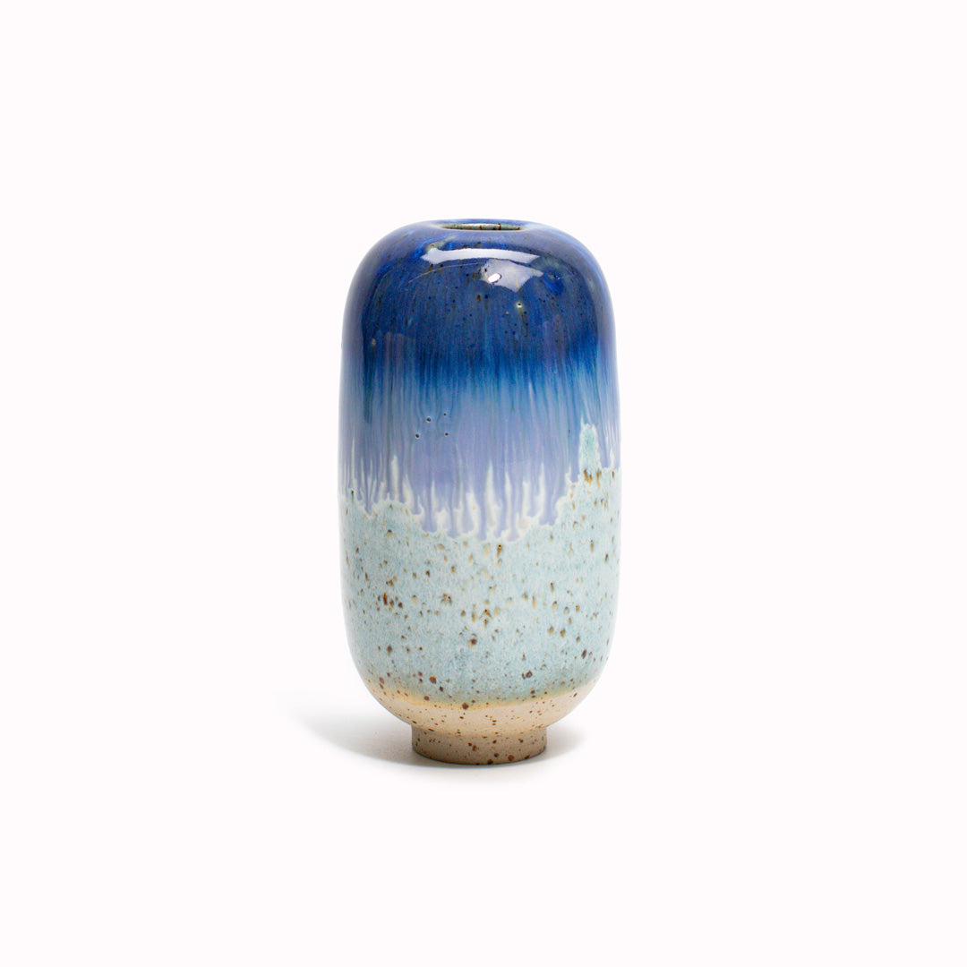 The Dark blue to light blue design is hand-thrown in watertight stoneware. Due to the rounded taper at the top of the vase, the glaze melts down the sides of the cylindrical vase mimicking melting ice.