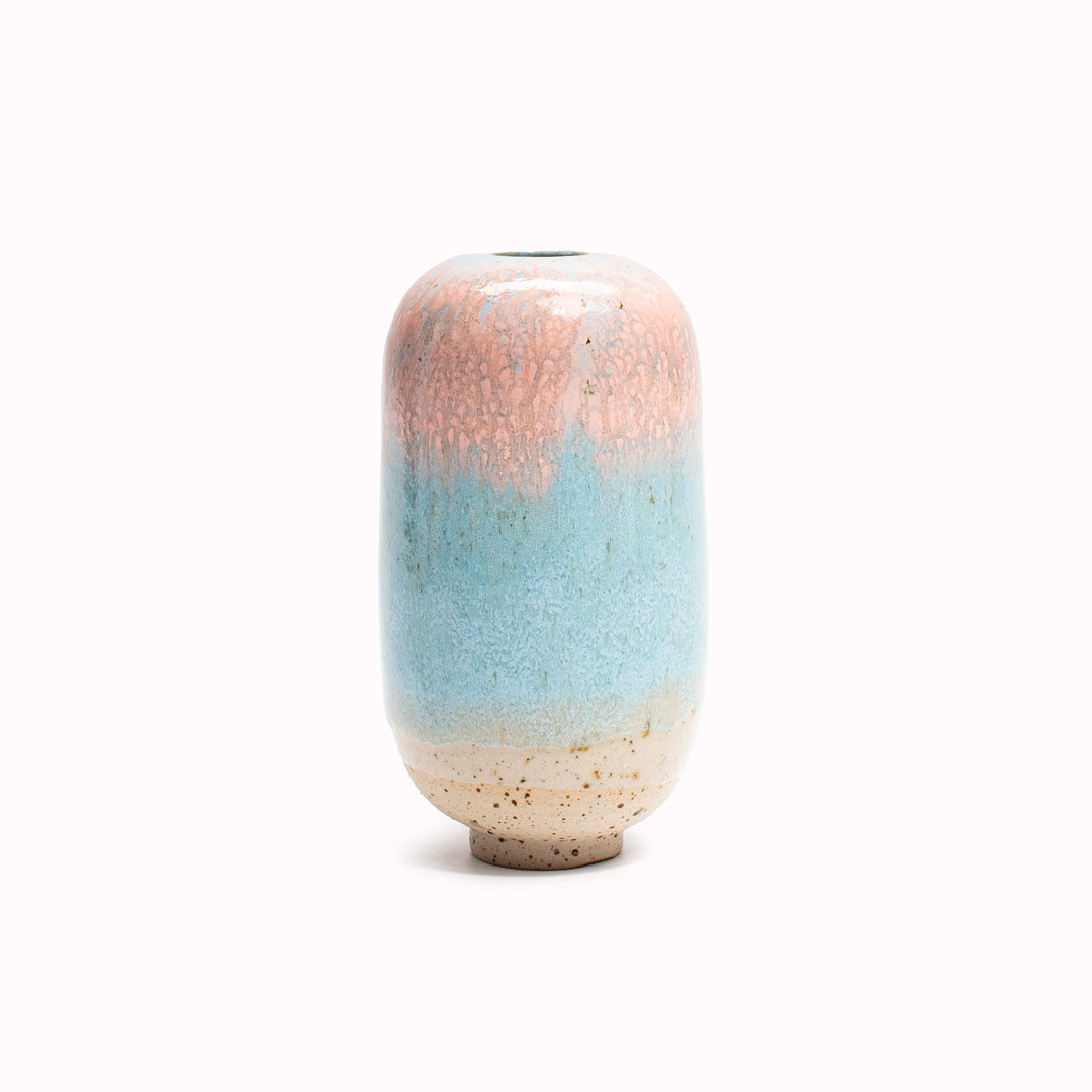 The pink over blue Bouncy Spring design is hand-thrown in watertight stoneware. Due to the rounded taper at the top of the vase, the glaze melts down the sides of the cylindrical vase mimicking melting ice.