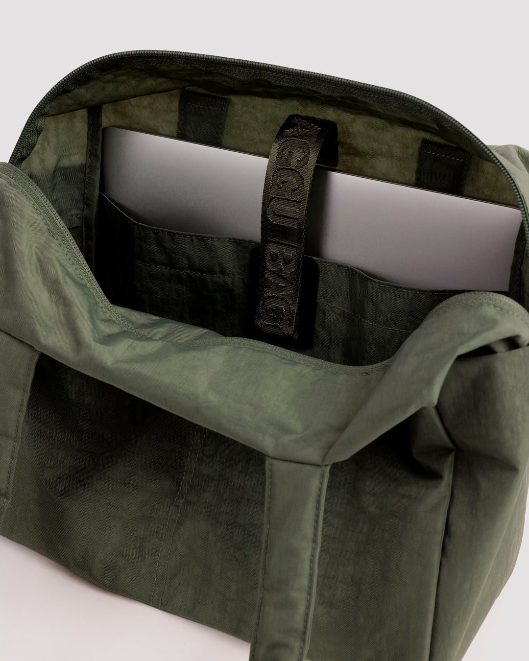 Made from recycled heavyweight nylon, it holds its shape without feeling rigid. The layout is considered: a zipped laptop sleeve sits to one side