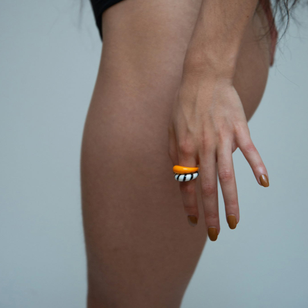 As worn by model, Carole is a bright orange handblown glass ring, handmade by Eyland Jewellery, who produce contemporary and colourful pieces of costume jewellery.