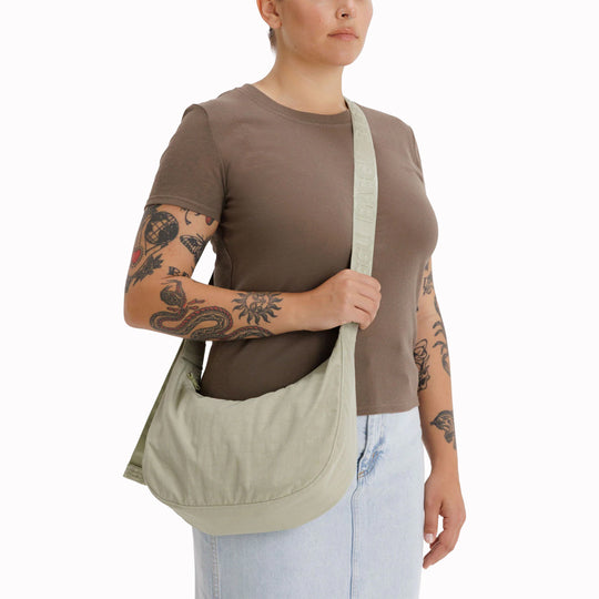 The Medium Crescent Bag in Celedon from Baggu is a stylish and versatile accessory that can complement any outfit. It is made of durable nylon and features a zippered main compartment