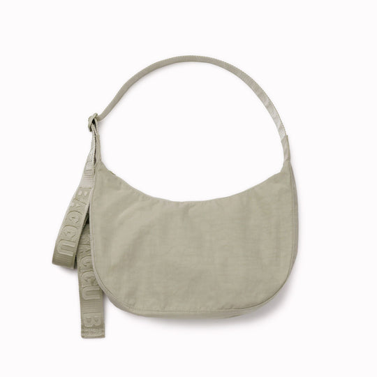 The Medium Crescent Bag in Celedon from Baggu is a stylish and versatile accessory that can complement any outfit. It is made of durable nylon and features a zippered main compartment