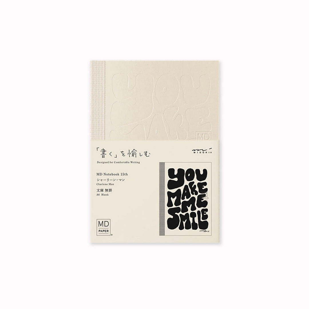 A6 plain paper notebook has an off white cover embossed with some ace artwork by Charlene Man featuring the words 'You Make Me Smile' in a hand-typography style. The MD paper logo is also embossed.