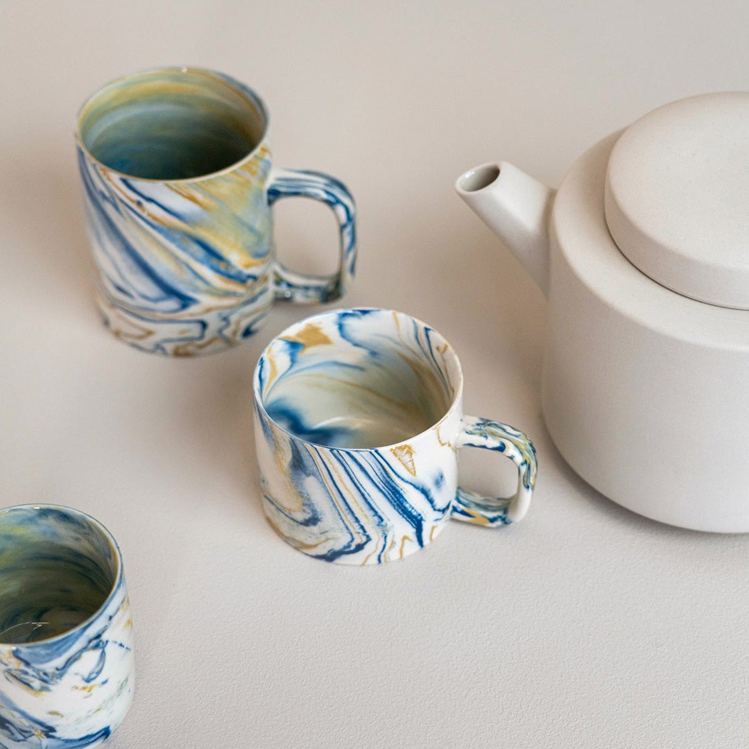 Collection of blue and mustard marbled gloss glaze cup from Dutch company Kinta, who produce contemporary ceramics and homeware.