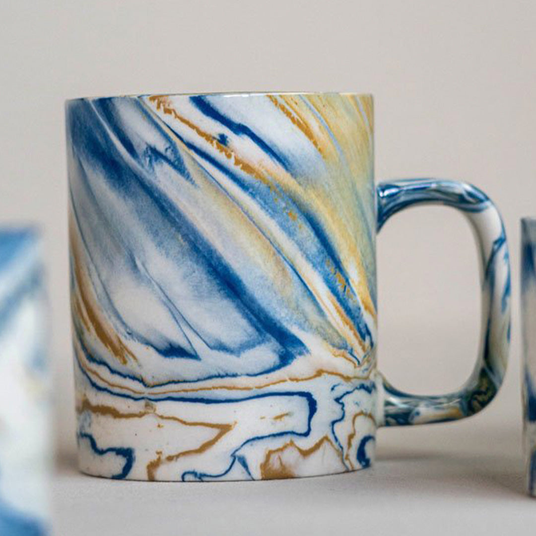 Detail of blue and mustard marbled gloss glaze mug from Dutch company Kinta, who produce contemporary ceramics and homeware. The stoneware mug has a striking marbled effect glaze with blue and mustard colouring. The glaze on the outside and on the interior is glossy and it holds 350ml