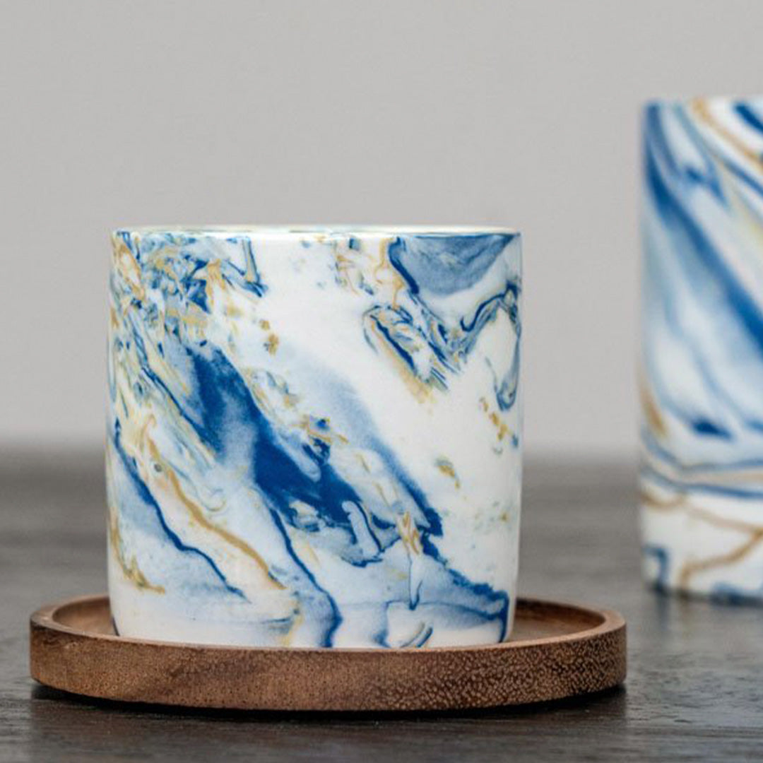 Detail of the blue and mustard marbled gloss glaze cup from Dutch company Kinta, who produce contemporary ceramics and homeware. The stoneware cup has a striking marbled effect glaze with blue and mustard colouring. The glaze on the outside and on the interior is glossy and it holds 150ml 