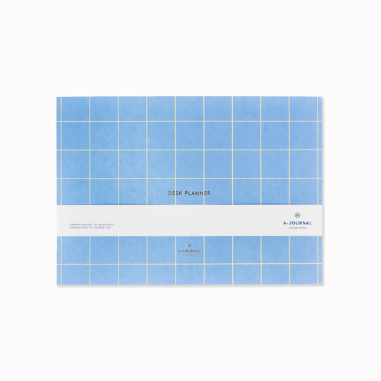 A weekly desk planner in pad format, designed to sit flat and stay visible. The layout is open and minimal, giving the week structure without crowding the page.