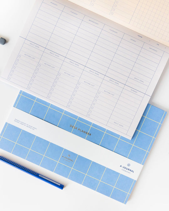 A weekly desk planner in pad format, designed to sit flat and stay visible. The layout is open and minimal, giving the week structure without crowding the page.