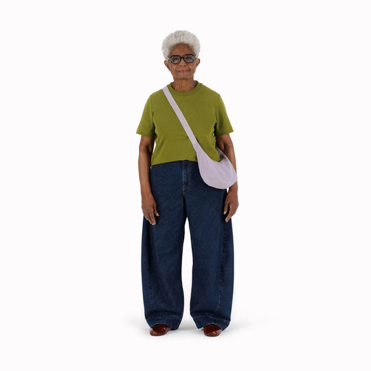 It is made of durable nylon and features a zippered main compartment, an interior slip pocket with integrated keyleash, and an adjustable shoulder strap. The bag has a curved shape that hugs your body and a sleek design that adds a touch of elegance